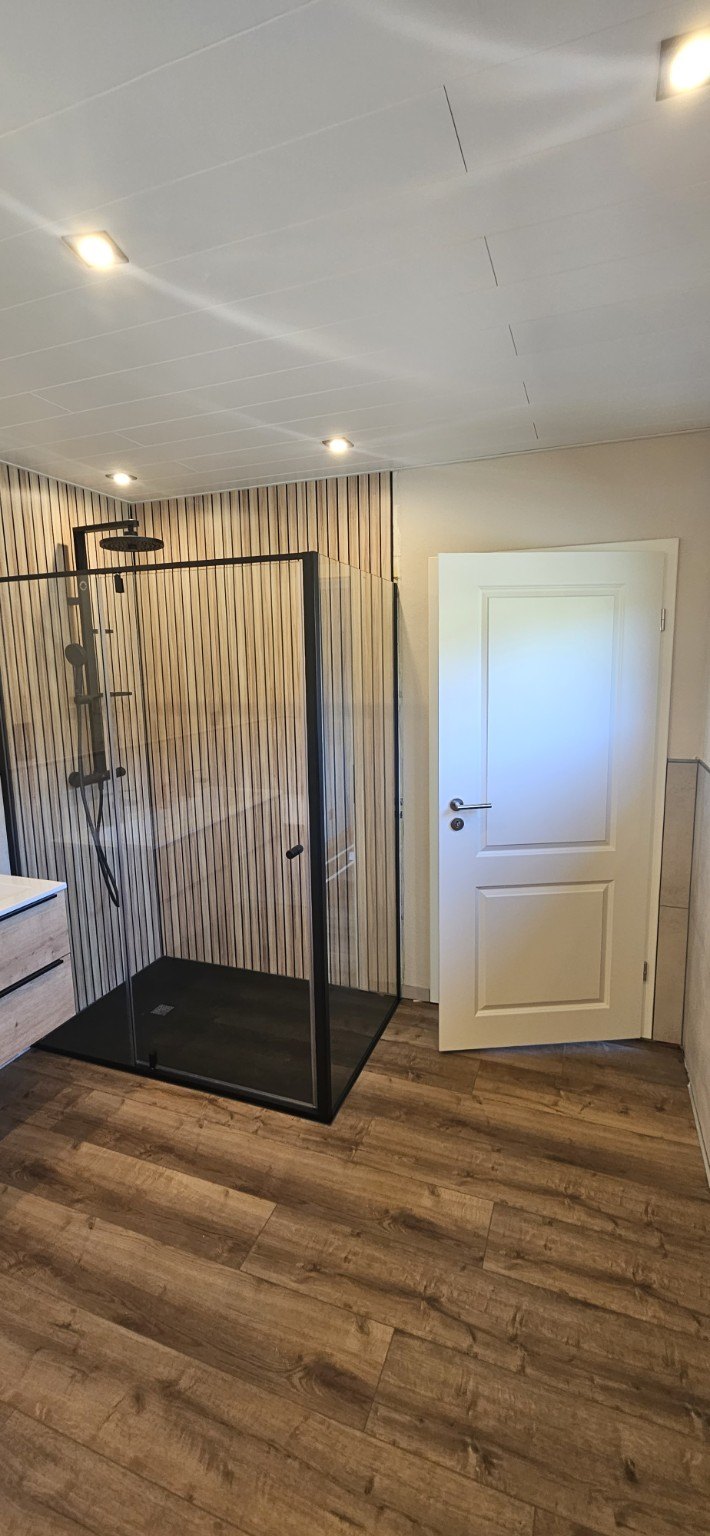 Duschbereich mit Glasabtrennung und Fliesen in Holzoptik