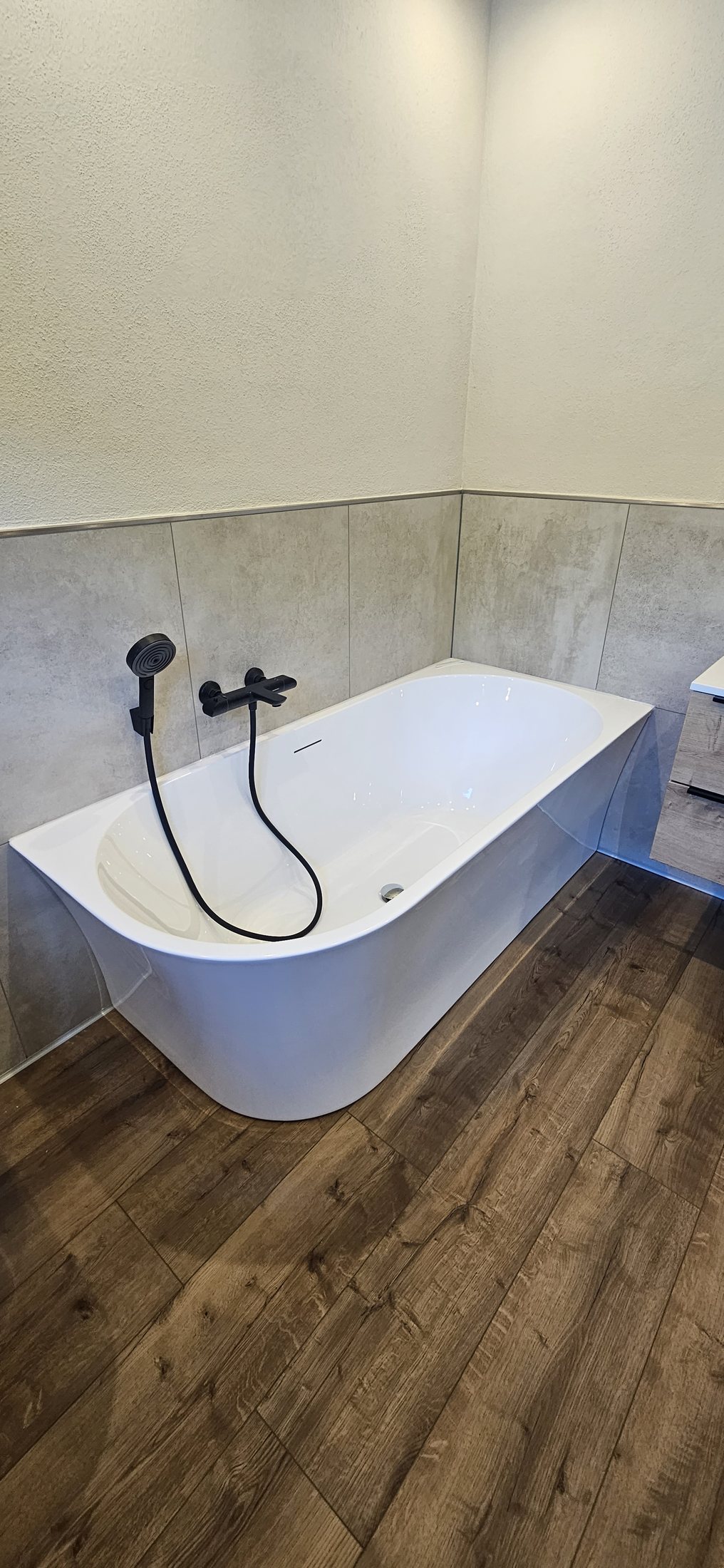 Badewanne mit Wandfliesen und Boden in Holzoptik