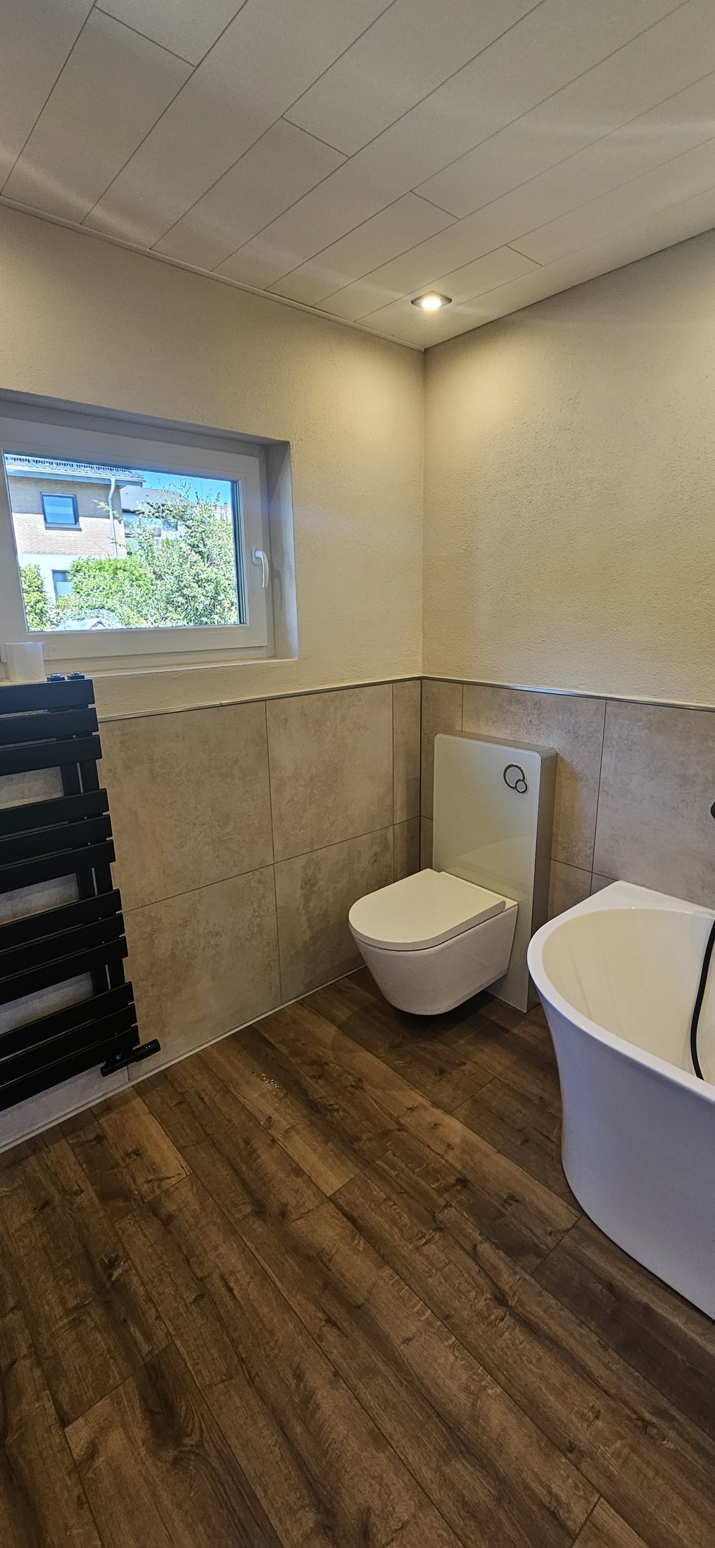 Bad mit WC, Waschtisch und Fliesen in Holzoptik